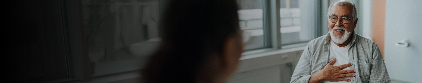 elderly male patient with hand over his heart