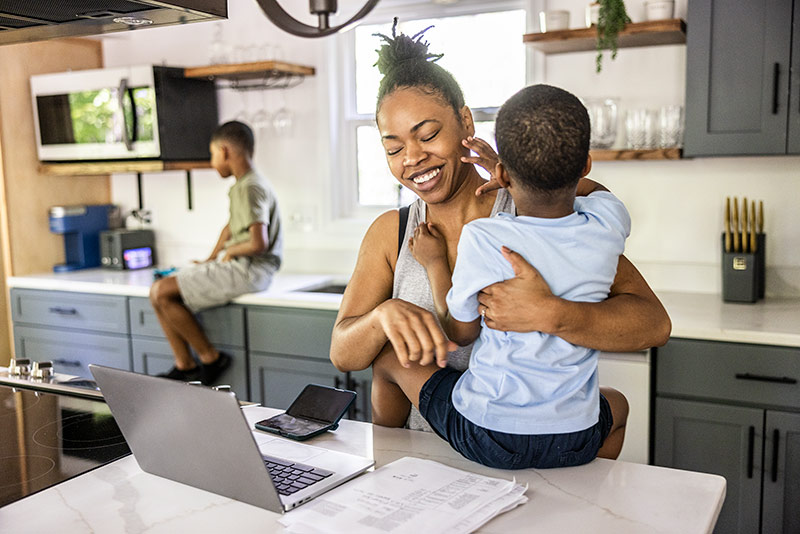 woman working while holding small child