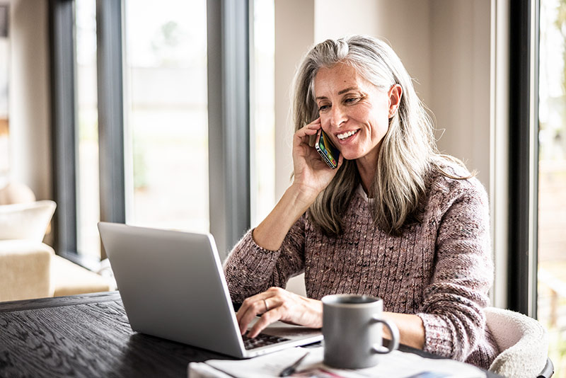 woman talking on the phone while working on her laptop
