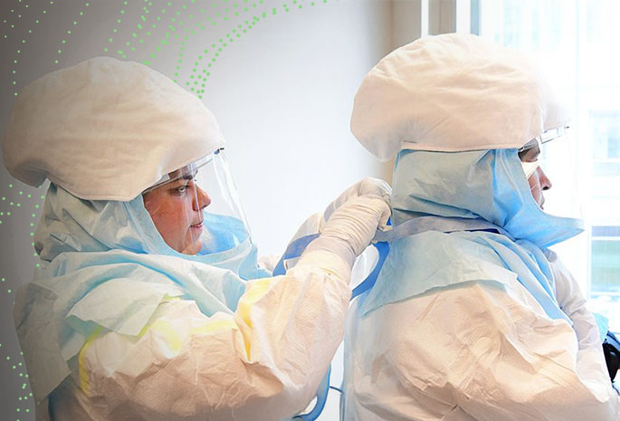 healthcare worker helping another with doffing suit