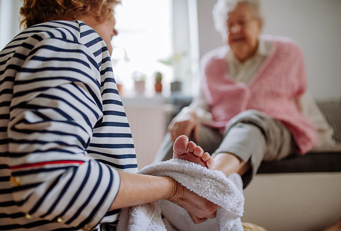 woman wiping the foot of an elderly woman