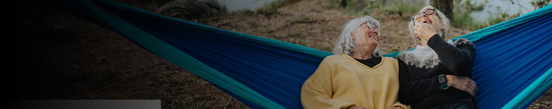 older lying across hammock and laughing